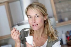 Женщина ест йогурт