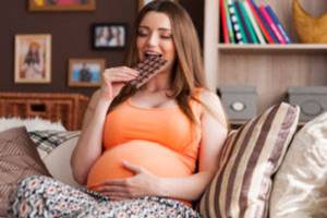 беременная девушка ест шоколадку