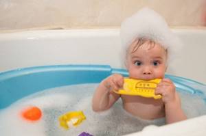Мальчик купается в ванне с термометром для воды