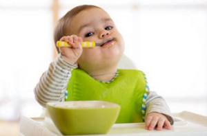 Маленький ребенок кушает с ложечки